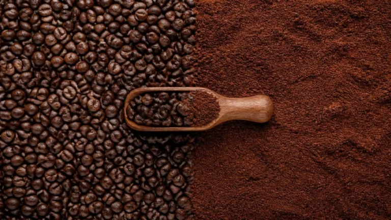 Whole roasted coffee beans beside ground coffee with a wooden scoop (illustrative image)